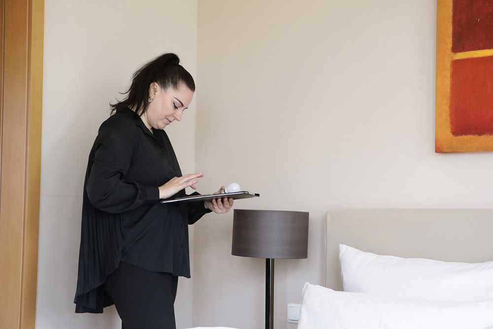 Eine Person in einem Hotelzimmer mit einer Checkliste auf einem Klemmbrett